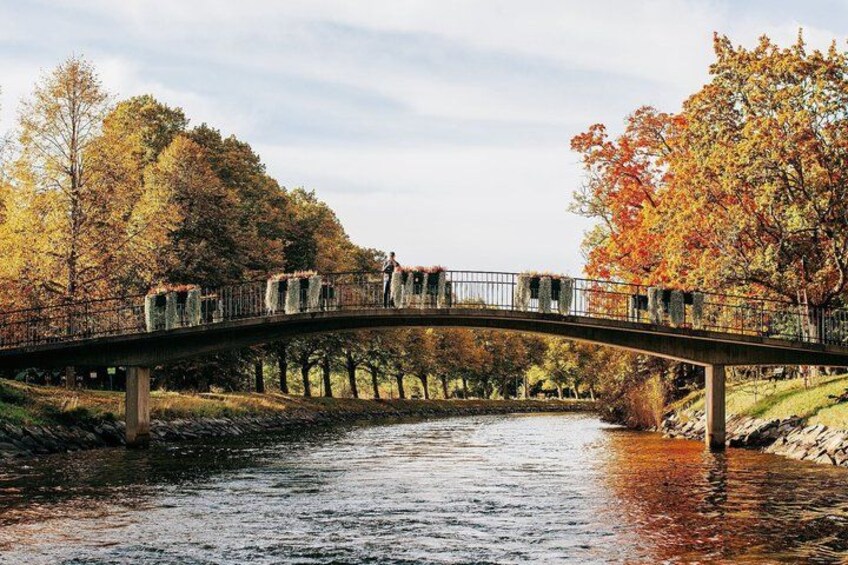 Un puente de piedra sobre un río, flanqueado por follaje otoñal y árboles a ambos lados. 2