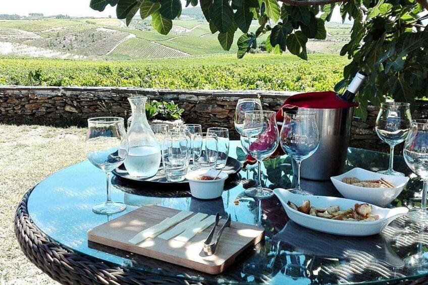 A round glass table set outdoors with wine glasses, a pitcher, and a bowl of nuts. 1