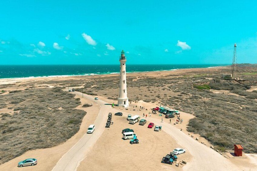Un phare, une plage de sable et un ciel bleu azur. 3