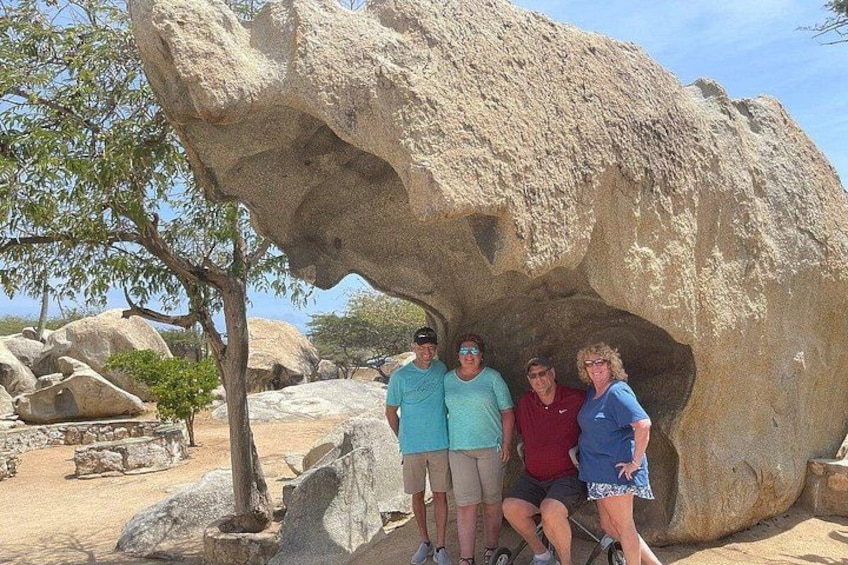 A large rock formation with people standing underneath it. 3
