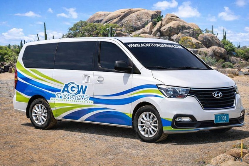 Una camioneta blanca con diseños de olas azules y verdes y el texto 'AGW TOURS' en la carrocería. 2