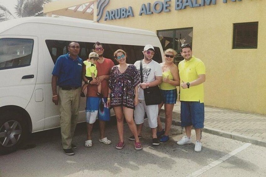 Un grupo de personas posando frente a un edificio con un letrero que dice 'ARUBA ALOE BALMI'. 4