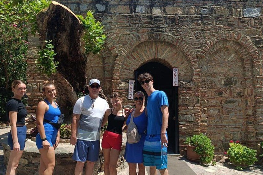 A group of people standing in front of a stone building with an arched entrance. 2