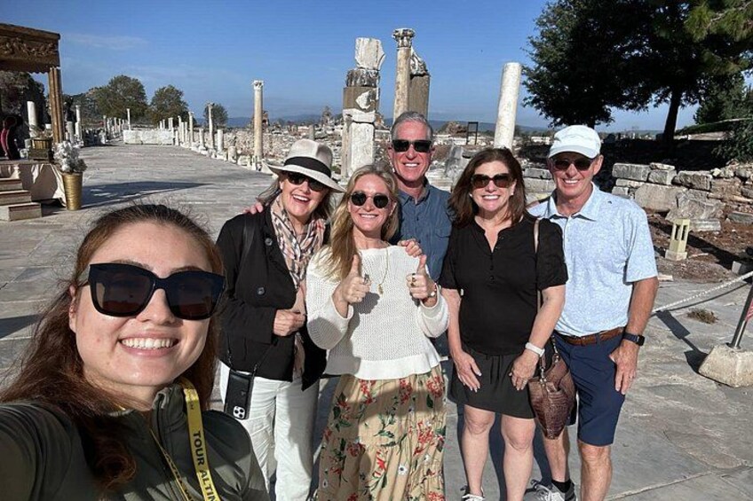 A group of people at an archaeological site with ancient ruins and columns in the background. 3