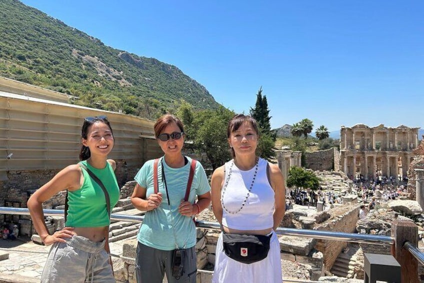 Tre persone in piedi di fronte a rovine antiche, con montagne sullo sfondo. 1