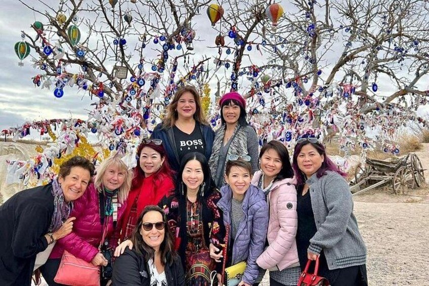 A group of people posing in front of a tree decorated with colorful ornaments. 2