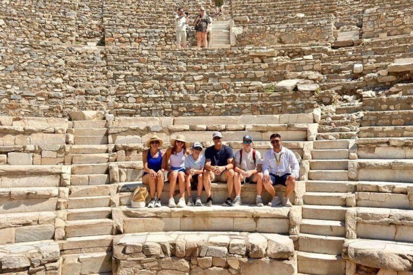 Tourists sitting on stone steps of an ancient amphitheater. 3