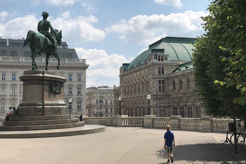 A statue of a man on horseback, a large building with a green roof, and a person walking on a bridge. 4