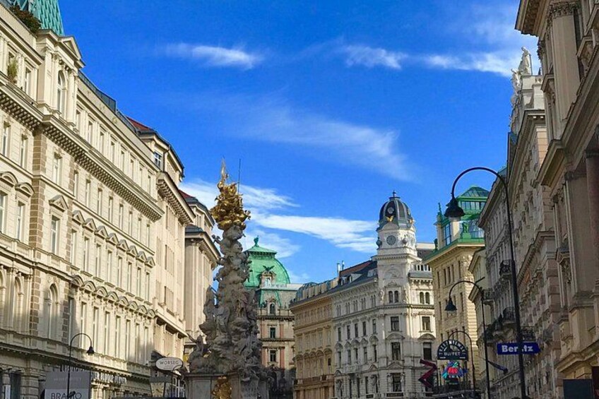 A historic building with ornate architecture, a clock tower, and a statue in the foreground. 3