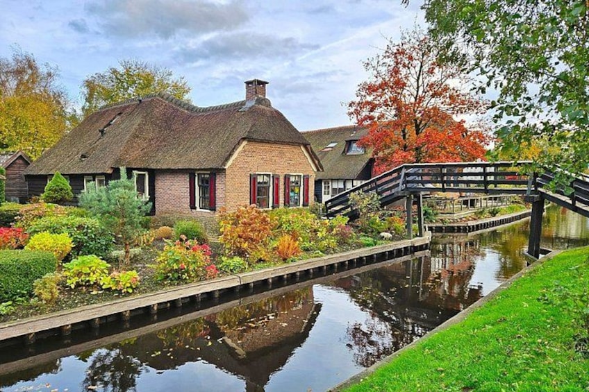 A traditional house with a thatched roof, a canal, and a wooden bridge. 2
