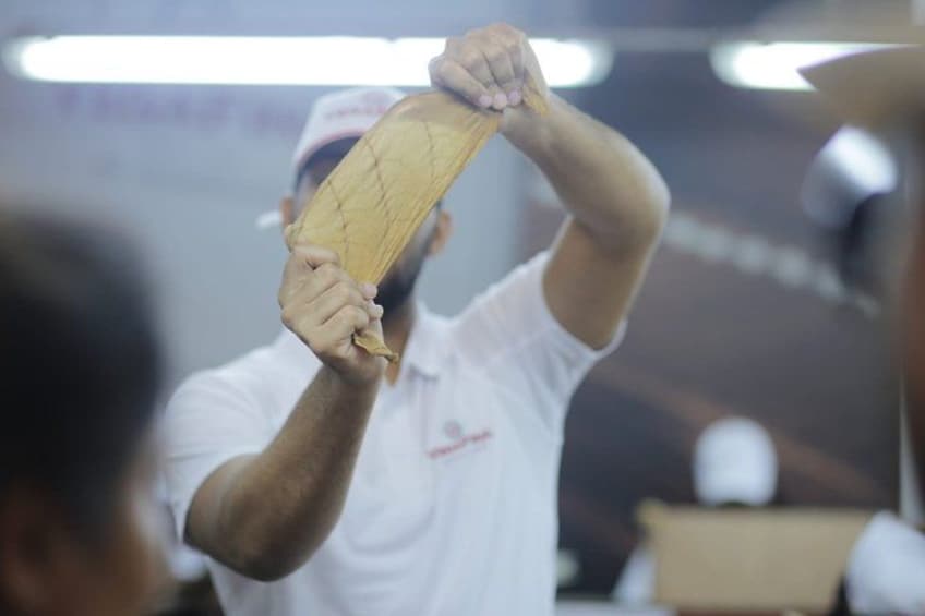 A person holding a wooden object, possibly a bat, in a workshop or factory setting. 5