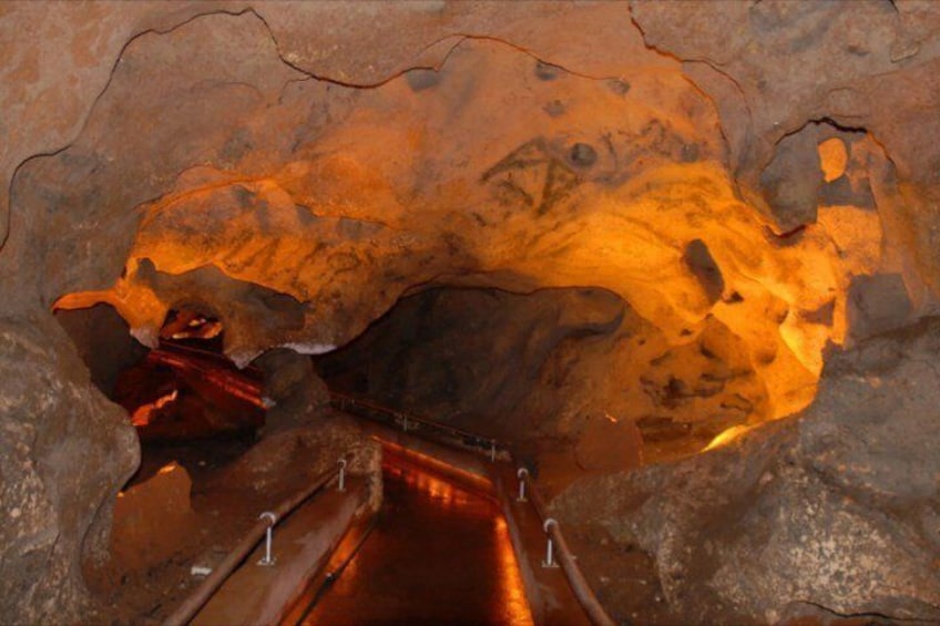 A cave interior with a metal staircase descending into a dimly lit area. 3