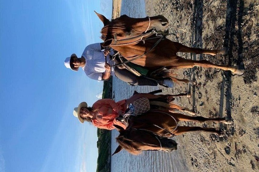 Tres personas montando caballos en una playa, con el océano al fondo. 3