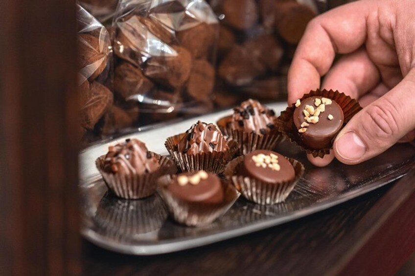 Una persona tiene un cioccolato con noci sopra, circondato da altri cioccolatini su un piatto. 3