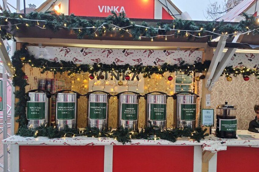 A festive beverage stand with Christmas decorations and labeled drink dispensers. 3