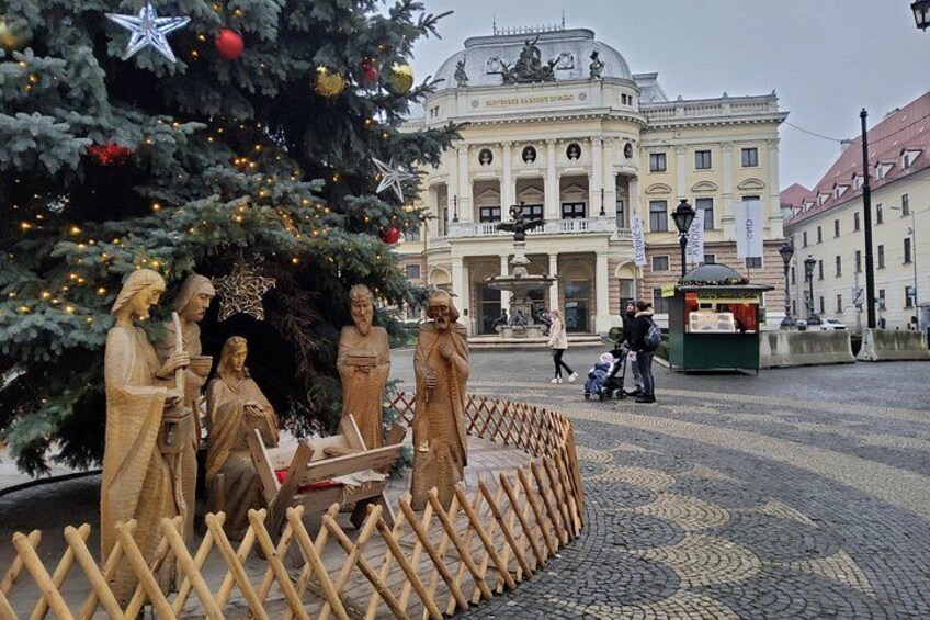 A nativity scene with a Christmas tree and a historical building in the background. 4