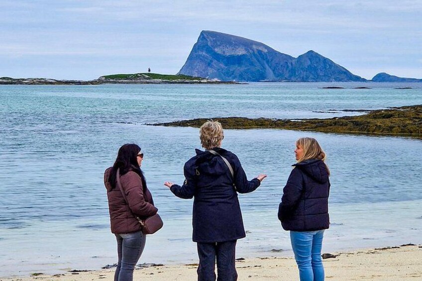 Drei Personen stehen an einem Strand und blicken auf einen großen Berg in der Ferne. 4