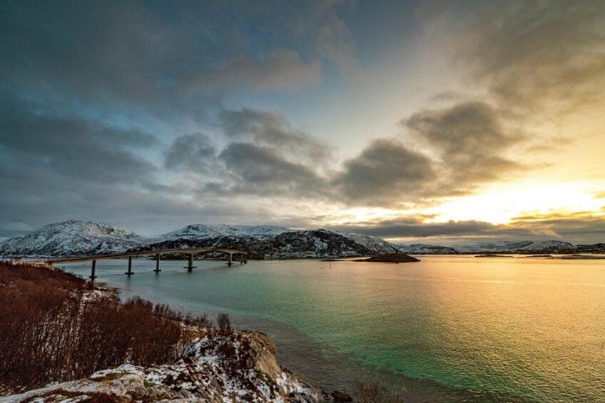 Eine Brücke über einen stillen See, im Hintergrund schneebedeckte Berge. 5