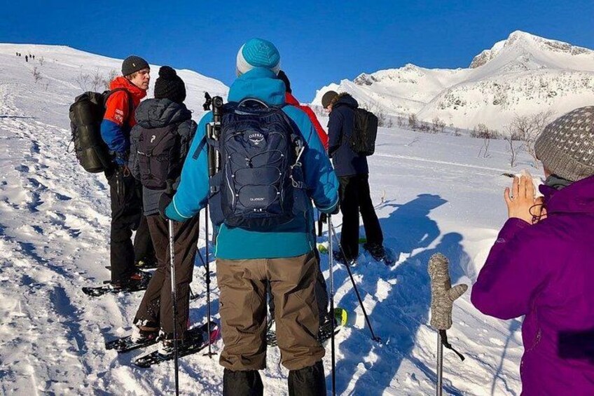 A group of people hiking in a snowy mountainous area with clear skies. 2