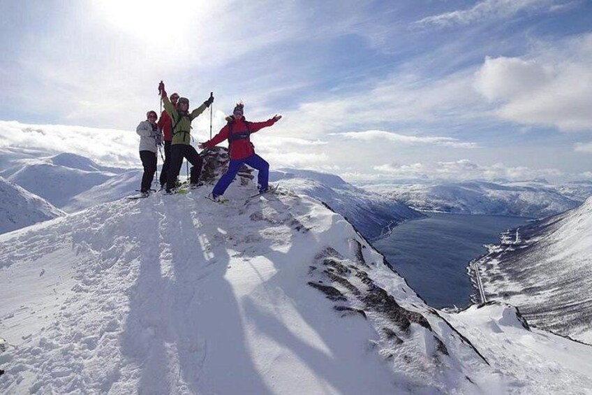 A group of people on a snowy mountain peak with a lake in the background. 5