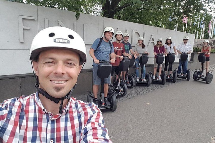 A group of people on segways in front of a wall with the word 'FINLAND' on it. 3