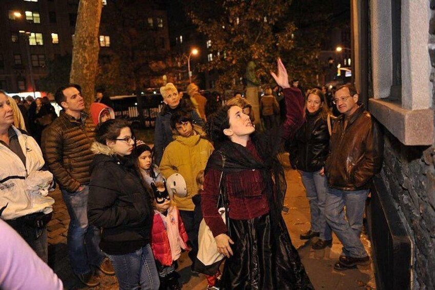 A group of people standing on a sidewalk at night. 2
