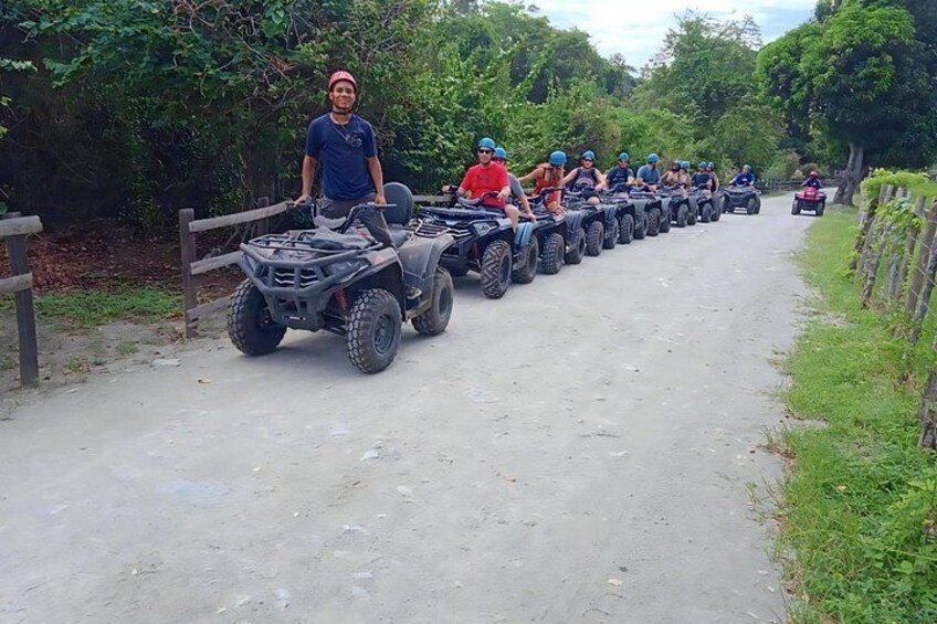 Un groupe de personnes conduisant des quads sur un chemin de terre, entouré de verdure. 4