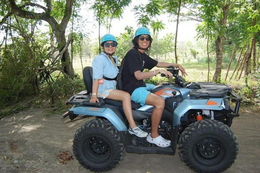 Deux personnes sont à bord d'un quad bleu dans une zone boisée. 2