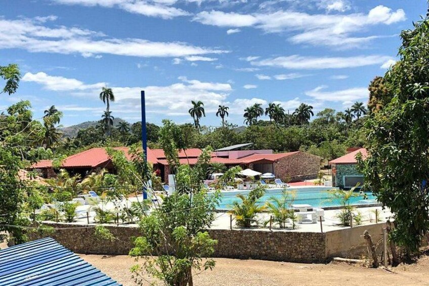 Un resort con piscina, palme e edifici dai tetti rossi. 3