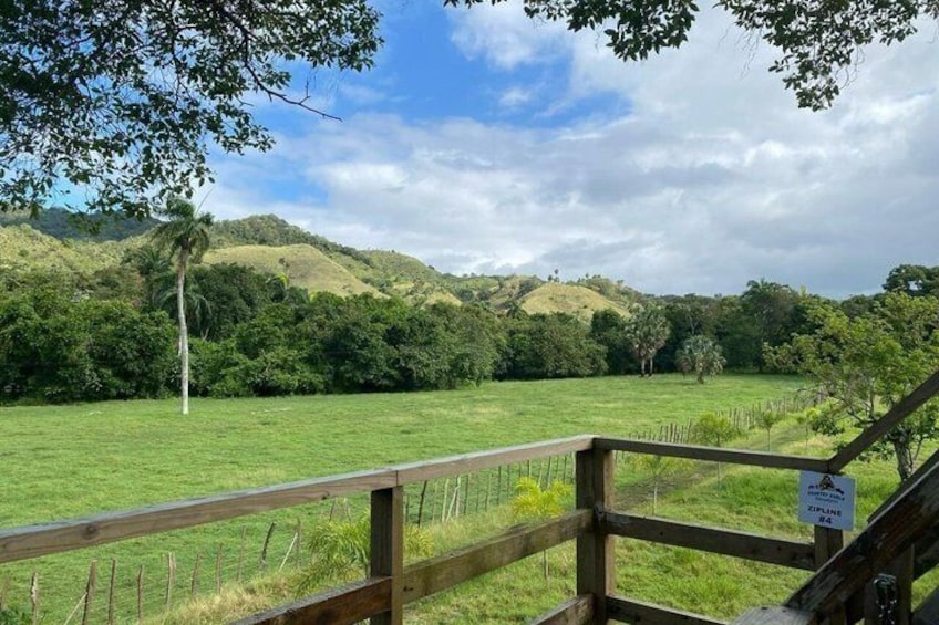 Una cerca de madera con vistas a un campo verde y colinas al fondo. 4