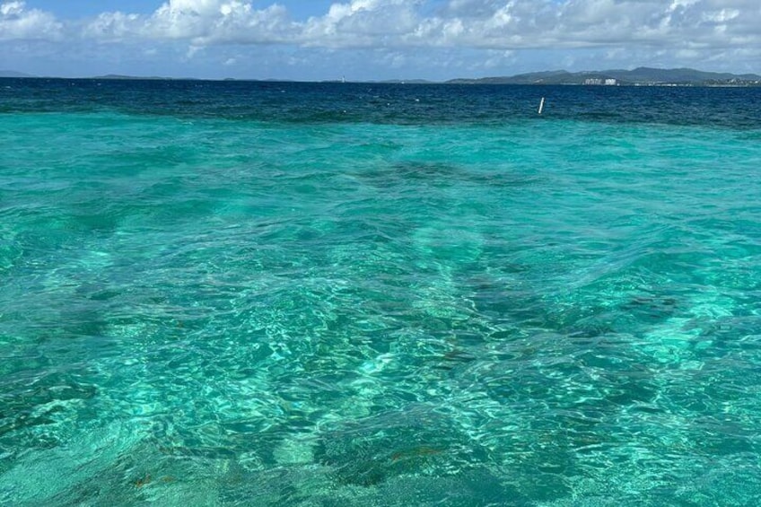 Klares türkisblaues Wasser mit einer fernen Küste und einem Boot. 1