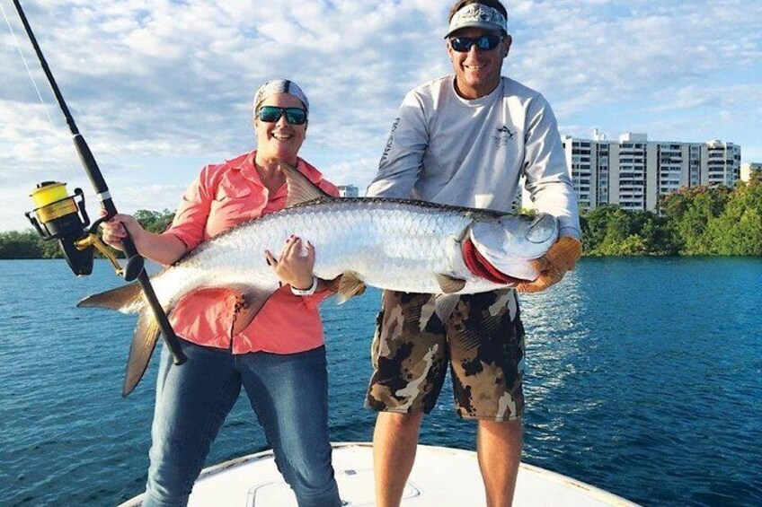 Two people on a boat holding a large fish. 1