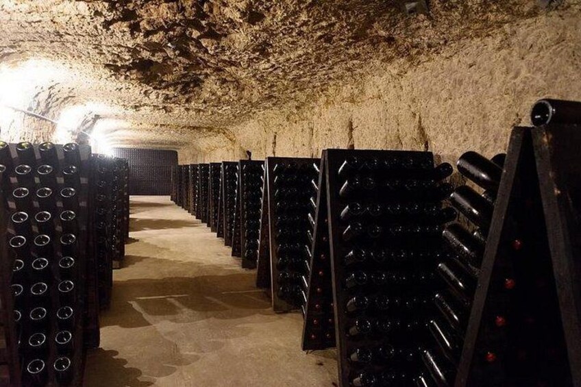 A wine cellar with rows of wine racks and a stone ceiling. 5