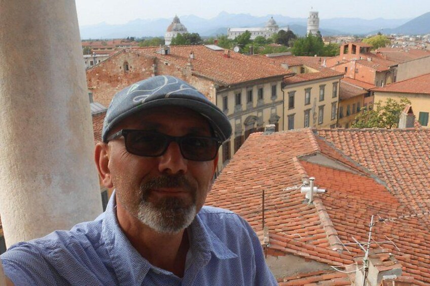 A man in a blue shirt and cap, a tiled roof, and historic buildings in the background. 3