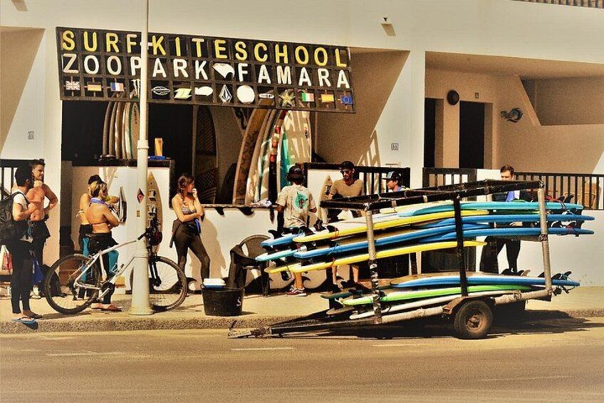 Una escuela de surf llamada 'Surf Kiteschool' con tablas de surf y una bicicleta. 4