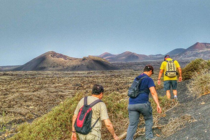 Trois personnes font de la randonnée sur un sentier rocailleux, avec un paysage montagneux en arrière-plan. 2