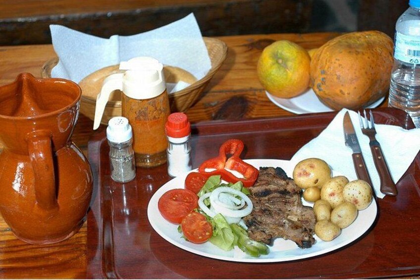 A plate of food with steak, potatoes, tomatoes, and lettuce, along with a jug, salt and pepper shakers, and a bottle of water. 5