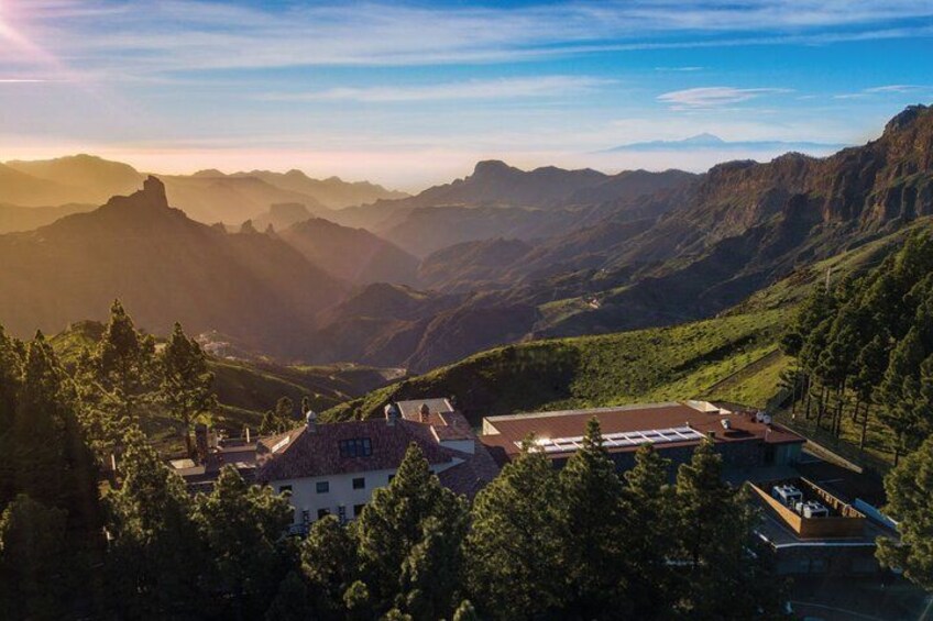 Paesaggio montuoso con un villaggio incastonato nella valle, circondato da vegetazione lussureggiante e cime lontane. 3