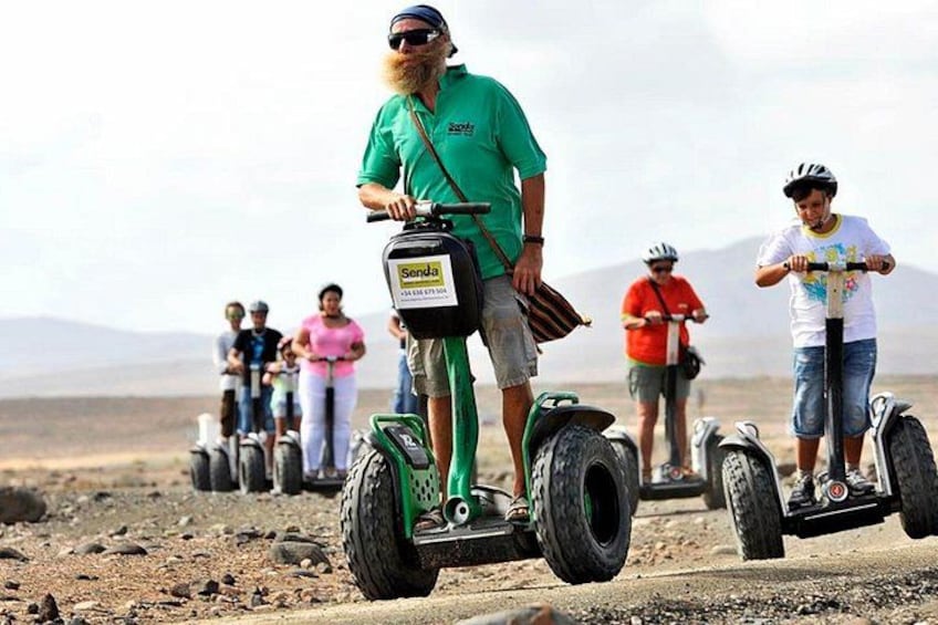 A person riding a Segway in a desert landscape with mountains in the background. 1