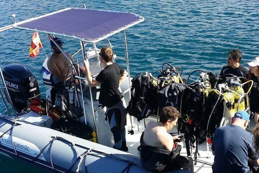 A boat with divers and equipment, a flag, and a person in a wetsuit. 5