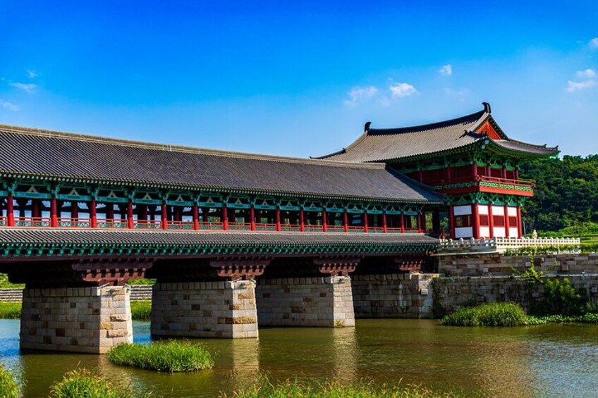 A traditional Korean bridge with ornate architecture, a stone foundation, and a clear blue sky. 4