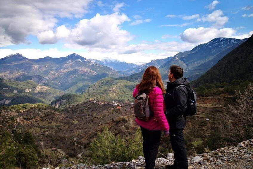Una pareja está de pie sobre un saliente rocoso con vistas a un paisaje montañoso y un valle en la distancia. 5
