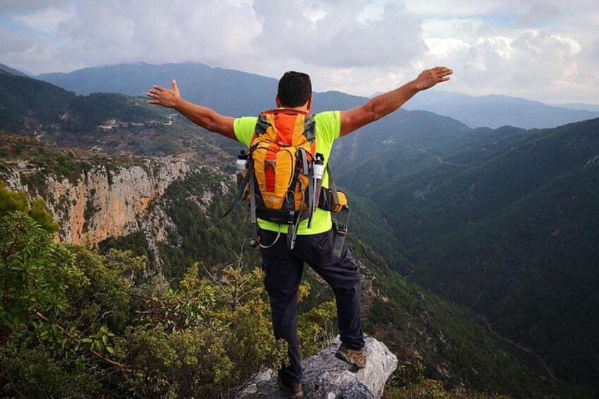 Una persona de pie sobre una roca, con los brazos extendidos, contemplando un paisaje montañoso. 4