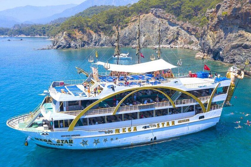 A large white cruise ship named 'MEGA STAR' with a curved deck, sailing in a turquoise sea with rocky cliffs in the background. 2