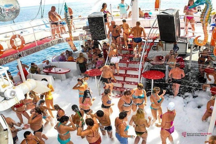 A crowded boat with people enjoying water activities, a disco ball, and a lifebuoy. 5
