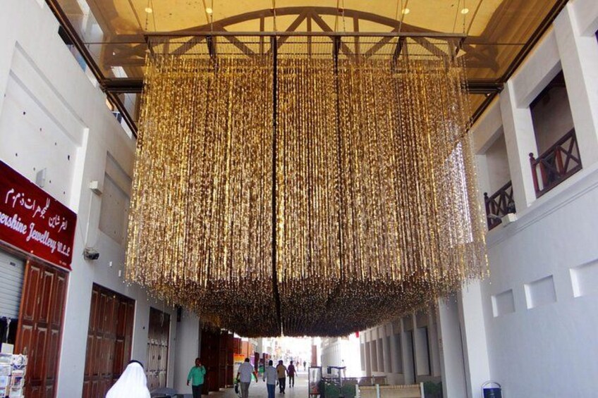 A large indoor space with a hanging decorative structure made of golden elements. 1