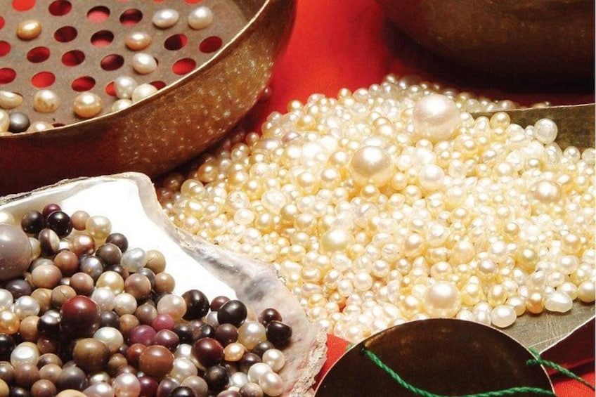 A variety of pearls in different colors and sizes, displayed in bowls and trays. 3