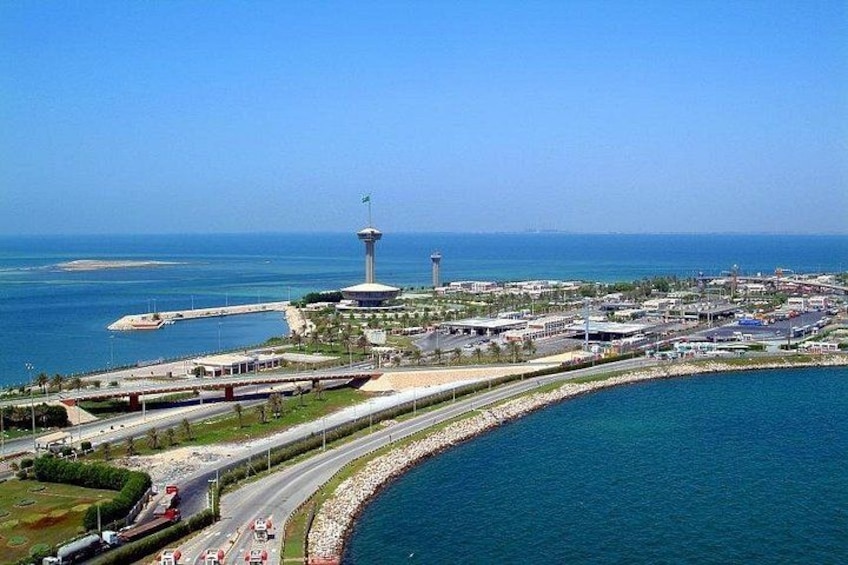 Una ciudad costera con una torre destacada, una carretera curva y un puerto deportivo. 5