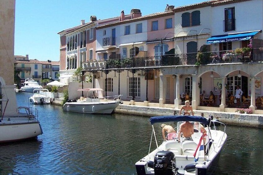 A canal with boats, buildings with balconies, and outdoor seating. 3