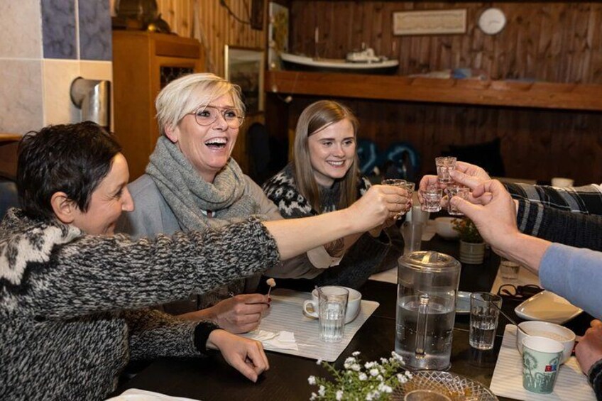 En grupp människor skålar med drycker vid ett träbord i en rustik miljö. 2